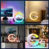 A collage of four images showing a crescent-shaped lamp with a digital display and multicolor lighting in different settings, including a desk, a nightstand, a dresser, and near a fireplace with Christmas decorations. Produktbild-Vorschau