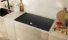 A modern kitchen countertop with a black induction hob, sink, and various kitchen accessories. Anteprima dell’immagine prodotto