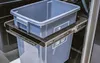 A close-up view of a pull-out trash bin system with a gray plastic bin on metal drawer slides. Produktbild-Vorschau