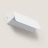 A white wall lamp is mounted on a light beige wall. Produktbild-Vorschau