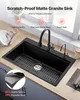 A black granite kitchen sink with a faucet and a sink grid, set in a modern kitchen countertop. Produktbild-Vorschau