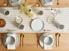 A table setting for four people with plates, bowls, cups, and cutlery arranged on a table runner. Náhľad obrázku produktu