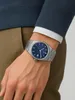 A person wearing a watch on their wrist. Voir les images du produit