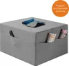 A gray ottoman with pockets on the sides, holding magazines and a remote, with a tablet and rolled-up magazine on top. Voir les images du produit