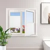 A white pleated window blind is shown installed on a window, with one section of the blind open to reveal a view of houses and a blue sky. A green potted plant is in the foreground. Produktbild-Vorschau