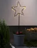 A star-shaped garden stake with LED lights is placed in a pot with greenery and apples, next to a basket of firewood. Podgląd zdjęcia produktu