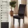 A dark brown upholstered dining chair with black wooden legs is shown in a room with a potted plant and natural light. Náhled obrázku produktu