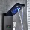 A modern black shower panel system with LED lights and a waterfall spout is installed on a gray tiled wall. Náhľad obrázku produktu