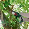A person is using a cordless chainsaw to trim a tree branch outdoors. Produktbild-Vorschau