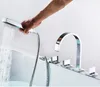 A hand is holding a shower head over a bathtub, with a modern faucet visible. Voir les images du produit