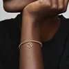 A close-up shot of a person's arm wearing a gold bracelet with a charm. Podgląd zdjęcia produktu