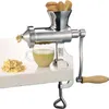 A manual juicer is clamped to a white surface, with wheatgrass being juiced into a glass cup. Produktbild-Vorschau