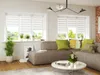 A modern living room with a sectional sofa, coffee table, and plants, featuring the product on the windows. Produktbild-Vorschau