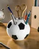 A soccer ball shaped pen holder on a wooden desk. Produktbild-Vorschau