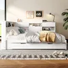 A white daybed with storage and a yellow blanket is shown in a bedroom setting with artwork on the wall and a plant in the corner. Produktbild-Vorschau