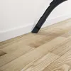 A vacuum cleaner nozzle is shown cleaning the edge of a wooden floor next to a white baseboard. Produktbild-Vorschau