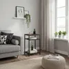 A side table with items on it, next to a sofa and in front of a window with curtains. Produktbild-Vorschau