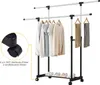 A double-tiered rolling garment rack with clothes hanging on the top rack and folded clothes and shoes on the bottom rack. An inset shows a close-up of the caster wheels. Anteprima dell’immagine prodotto