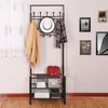 A black metal coat rack with shelves, holding a coat, hat, scarf, and bag. Several framed pictures are on the wall behind it. Náhled obrázku produktu