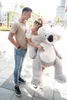 A couple is posing with a large teddy bear on a sidewalk. Náhľad obrázku produktu