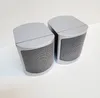 Two silver speakers are placed on a white surface against a light gray background. Produktbild-Vorschau