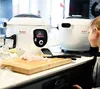 A child is looking at a Tefal Cook4me+ smart multi-cooker on a kitchen counter. Podgląd zdjęcia produktu