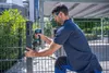 A man is using a Bosch cordless impact wrench to install a fence post. Voir les images du produit