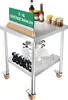 A stainless steel work table with wheels, displaying various kitchen items and a sign. Produktbild-Vorschau