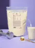 A bag of vegan protein powder with a glass of milk, a scoop of powder, and a dumbbell. Produktbild-Vorschau