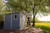 A person is using a ladder to reach the top of a shed in a garden. Anteprima dell’immagine prodotto