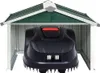 A robotic lawnmower is parked inside a green and white metal garage. Náhľad obrázku produktu