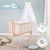 A wooden baby crib with a canopy and bedding, set against a light blue wall. Produktbild-Vorschau
