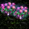 Two illuminated solar flower lights are planted in a garden at night. Náhled obrázku produktu