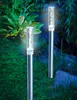 Two solar-powered garden lights are illuminated in a garden at dusk. Produktbild-Vorschau