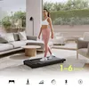 A woman is walking on a treadmill in a modern living room. Podgląd zdjęcia produktu