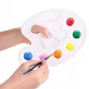 A child's hands are holding a paint palette with various colors of paint on it, and a paintbrush is dipping into one of the colors. Produktbild-Vorschau