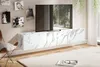 A modern living room with a wall-mounted TV stand featuring a marble-like finish, a television, and decorative photos on the wall. Produktbild-Vorschau