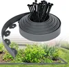 A roll of gray plastic lawn edging and a bundle of black stakes are shown in the foreground, with a garden bed and house in the background. Produktbild-Vorschau
