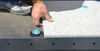 A person's hand is shown placing a paving stone onto a support system on a rooftop or balcony. Anteprima dell’immagine prodotto