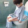 A young child is sitting on a toilet with a potty training seat, looking at a tablet. Náhled obrázku produktu