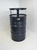 A dark gray barrel-shaped table with a circular top, standing in a corner against white walls. Produktbild-Vorschau