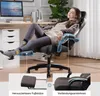 A woman relaxing in a gaming chair with an extended footrest and adjustable armrests in a home office setting. Produktbild-Vorschau