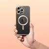 A hand holds an iPhone 12 Pro Max with a clear MagSafe case, showcasing the camera array and the MagSafe ring. Produktbild-Vorschau