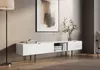 A modern white TV stand with black metal legs is shown in a living room setting. Produktbild-Vorschau