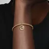 A close-up shot of a person's arm wearing a gold bracelet with a charm. Podgląd zdjęcia produktu