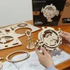 A person's hands are assembling a wooden 3D puzzle model of a perpetual calendar on a wooden table, with the product's packaging and unassembled parts visible. Anteprima dell’immagine prodotto