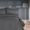 A bed with dark gray striped bedding, a floor lamp, and textured wall. Produktbild-Vorschau