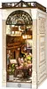 A miniature diorama of a Parisian-style arcade dating scene, featuring a cafe and bookshop. Podgląd zdjęcia produktu