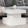 A white coffee table with books and a vase on it, placed in front of a gray sofa. Voir les images du produit
