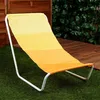 A yellow and orange striped lounge chair is placed on green artificial grass, with a wooden fence and green foliage in the background. Voir les images du produit